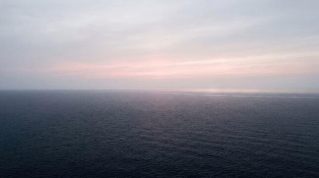 Soft Pink Sunrise Over Calm Sea Horizon Minimalist Ocean View. Concept of water, sky, landscape, calm water, serene landscape, tranquil sea. Copy space.
