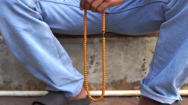 Hand Holding Prayer Beads for Islamic Dhikr
Close-up of a Muslim man's hand holding traditional wooden prayer beads (tasbih) while performing dhikr and Islamic prayer in a peaceful setting.