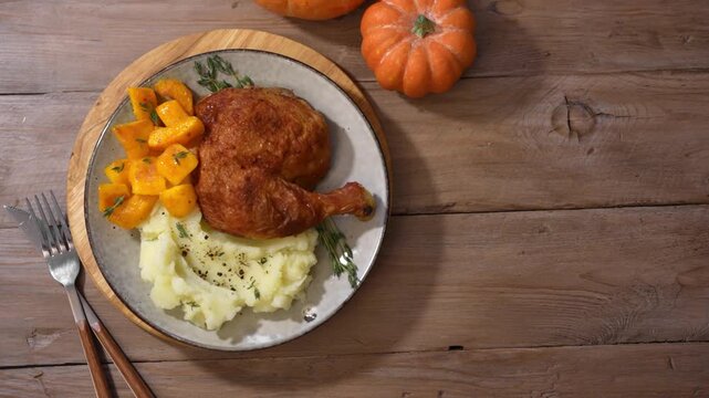 Roasted chicken quarter with glazed pumpkin, herbs and mashed potato, top view. Portion of festive autumn meal for Thanksgiving. Healthy seasonal food.
