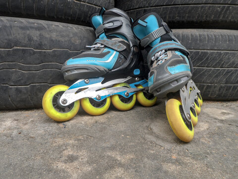 A pair of blue inline skates are placed upright, leaning against each other.
