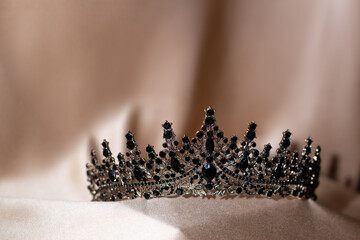 Elegant Black Crystal Crown, Tiara on Beige Gold Fabric. © Elina Leonova