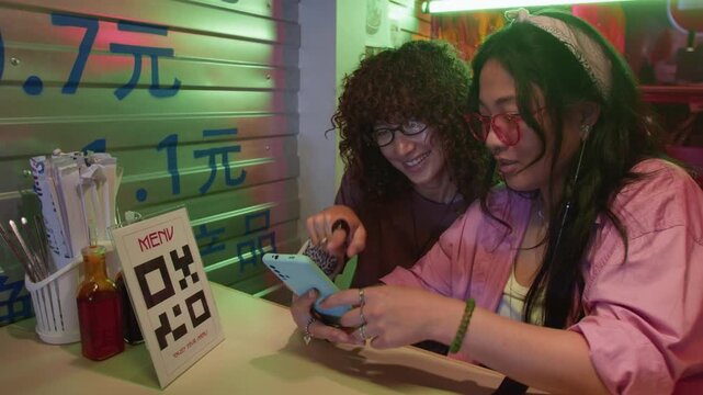 Young Asian women scanning QR code menu with smartphone in cafe. Footage is perfect for commercial projects showcasing contactless ordering and modern restaurant technology