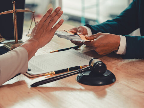 Lawyer hand gesturing stop to refuse money cash bribe offered by client in office