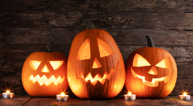 Halloween pumpkins and burning candles on wooden background