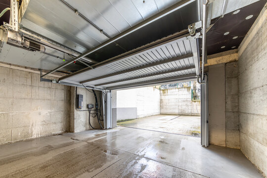 Modern Garage with Open Automatic Sectional Metal Door and Overhead Mechanism, Showing Entrance to Outdoor Driveway