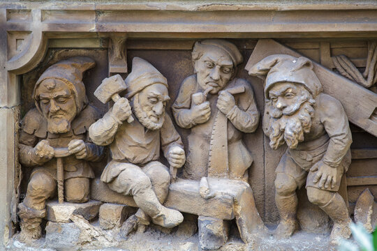 Detailed Stone Relief Carving of Working Gnomes at the Heinzelm&auml;nnchenbrunnen Fountain in Cologne, Germany. German Folklore and Historic Landmark