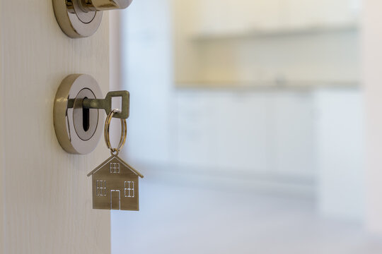 Open door to a new home with key and home shaped keychain. Mortgage, investment, real estate, property and new home concept