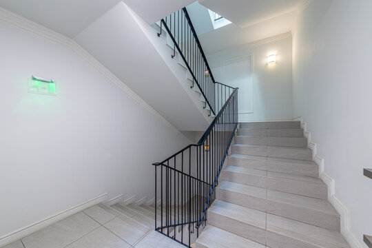 Modern stair case between floors. Stairs with metallic rail in modern building. Interior of a contemporary apartment or office building. Architecture and real estate background.