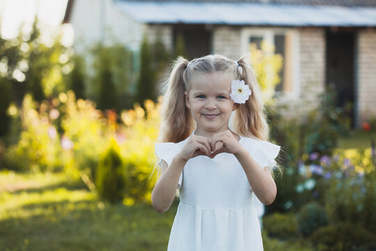 a cute five-year-old girl in a white dress is playing in a green summer garden. happy childhood