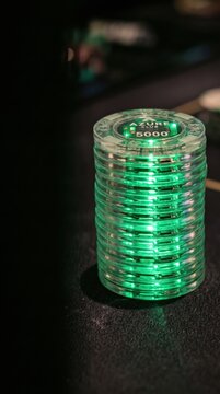 Glowing electronic casino chips stacked on a dark table. Advanced biometric surveillance and digital security monitoring in gaming environments.
