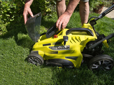 Male Gardener inserting a Lithium Ion battery on a electric cordless lawnmower