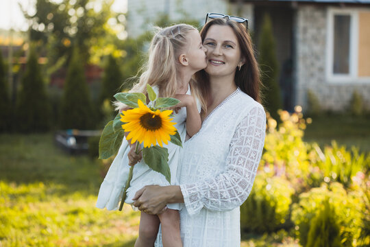 a cute five-year-old girl with mother in a white dress are playing in a green summer garden. happy childhood