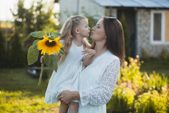 a cute five-year-old girl with mother in a white dress are playing in a green summer garden. happy childhood