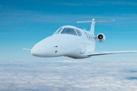 White executive jet plane fly in the air above the clouds