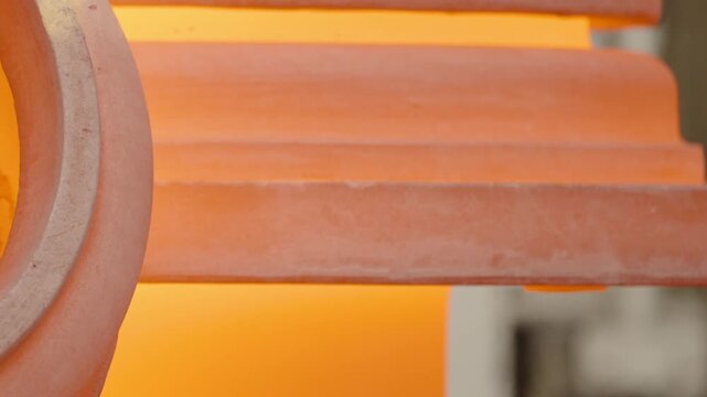 Curved refractory steel glows orange against the bright furnace interior in a tight engineering foundry close up.