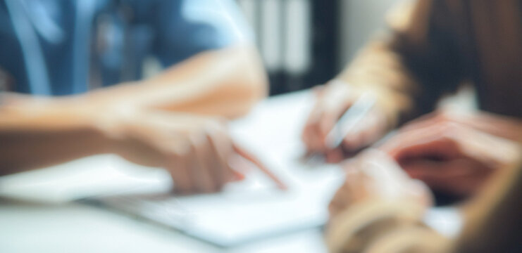 A close-up of hands engaged in a collaborative discussion over documents on a table, emphasizing teamwork and communication in a professional setting.