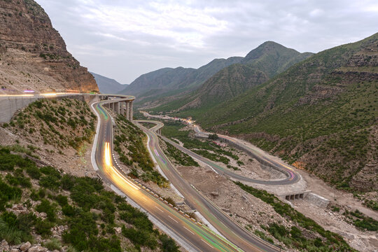 View of Fort Munro Road winding through the mountainous landscape of the Sulaiman Range with long exposure light trails from vehicles in Fort Monroe, Punjab, Pakistan.