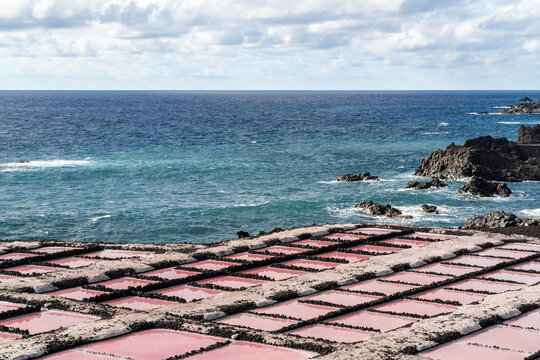 View of the pink salt pans at Salinas de Fuencaliente with black volcanic rock borders and the blue Atlantic Ocean in Santa Cruz de La Palma, Canarias, Spain.