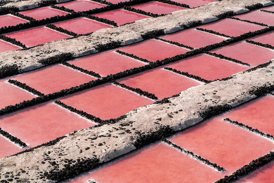View of the vibrant pink salt pans at Salinas de Fuencaliente with dark volcanic rock borders in Santa Cruz de La Palma, Canarias, Spain.