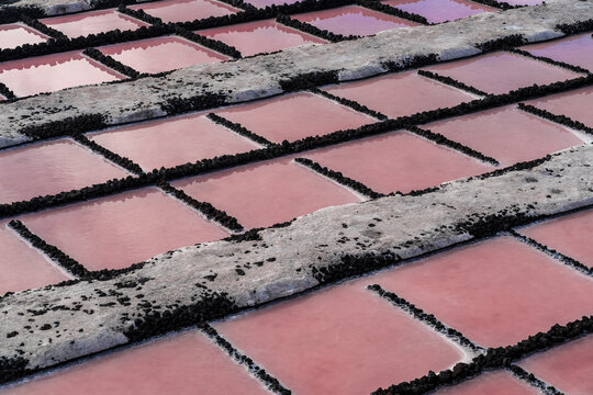 View of the pink salt pans at Salinas de Fuencaliente with geometric volcanic rock borders in Santa Cruz de La Palma, Canarias, Spain.