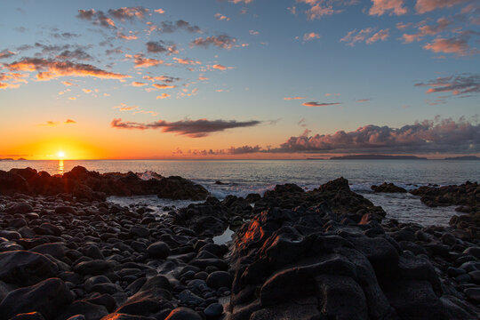 Golden sunset over the rugged black volcanic rock coastline and calm Atlantic ocean in Madeira, capturing a scenic and peaceful nature landscape at dusk.