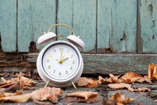 End of daylight saving time in autumn, winter time changeover, alarm clock fall back switch, colorful foliage, backyard