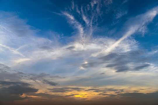 View of a vibrant sunset with golden light illuminating wispy clouds against a deep blue sky in Jahanian, Punjab, Pakistan.