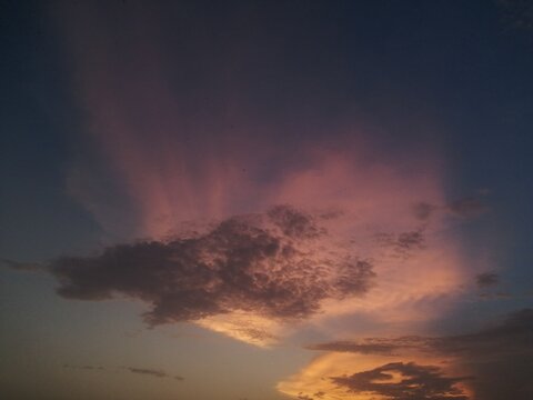 View of a dramatic sunset sky with vibrant pink and orange clouds illuminated by the fading light over the horizon in Jahanian, Punjab, Pakistan.