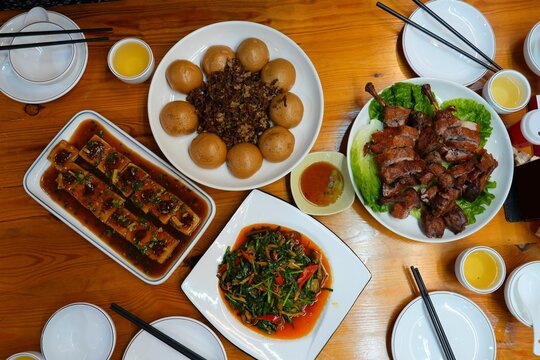 Restaurant table with many dishes in rural Guangdong, China. Cantonese cuisine and Hunan cuisine. Stuffed tofu, waipo cai, duck legs and vegetable stir fry.