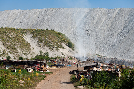 View of the Jagnjilo waste disposal site with smoke rising from burning refuse, makeshift shacks, and a large slag heap in the background in Pljevlja, Pljevlja Municipality, Montenegro.