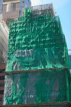 Construction site in Central, Hong Kong. Bamboo scaffolding covered by protective plastic net. Building renovation works.