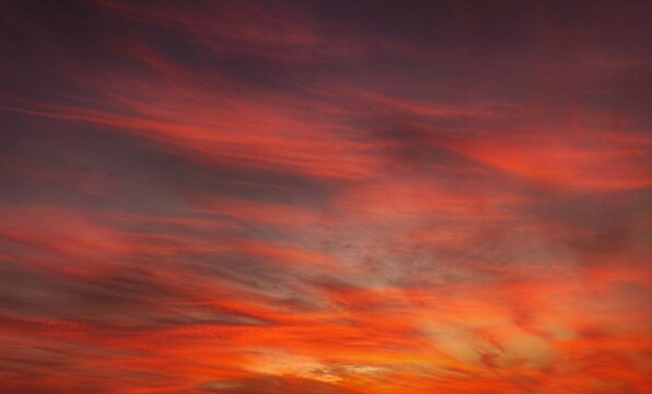 View of a vibrant sunset with streaks of orange, red, and purple clouds filling the sky over Jahanian, Punjab, Pakistan.