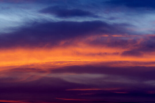 View of a vibrant sunset with intense orange and red clouds contrasting against a deep blue sky in Jahanian, Punjab, Pakistan.