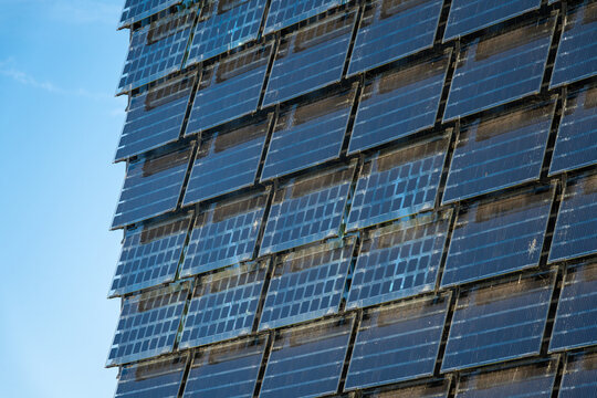 View of vertical solar panels mounted on a building facade under a clear blue sky in The Netherlands.