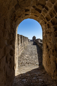 View of Elvas Castle with its ancient stone walls, cobblestone walkway, and a watchtower under a clear blue sky in Elvas, Portalegre, Portugal.