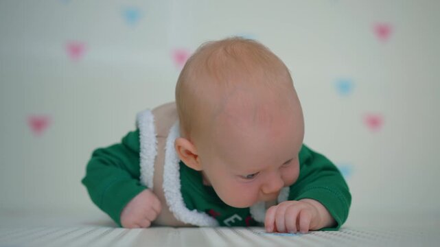 Three month old baby in christmas outfit touching textured rug.