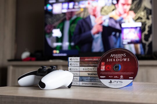 BRECHT, BELGIUM &ndash; August 28, 2026: Portrait of a stack of PS5 games, a controller, a physical game disc and a blurred playstation home screen in the background.
