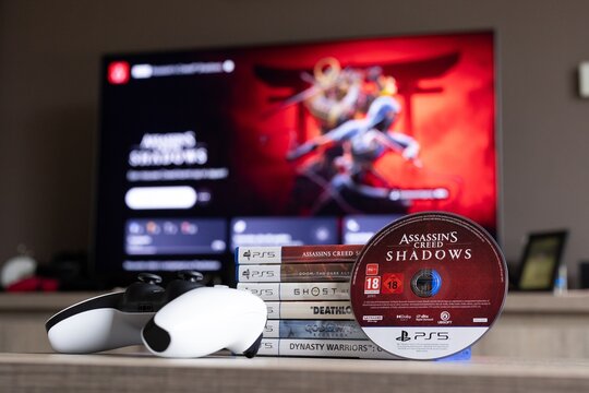 BRECHT, BELGIUM &ndash; August 28, 2026: Closeup portrait of a stack of PS5 games, a controller, a physical playstation game disc and a blurred home screen in the background.
