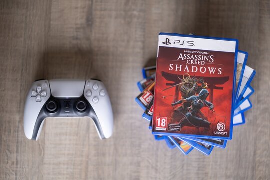 BRECHT, BELGIUM &ndash; August 28, 2026: Closeup portrait of a stack of PS5 playstation games with a playstation controller lying next of it on a table, highlighting physical gaming media.