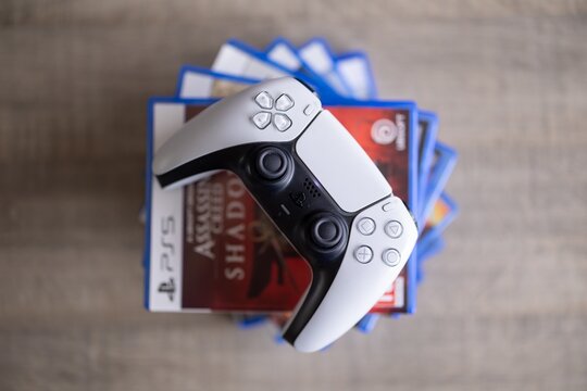 BRECHT, BELGIUM &ndash; August 28, 2026: Closeup portrait of a stack of PS5 playstation games with a playstation controller lying on top of it, highlighting physical gaming media.