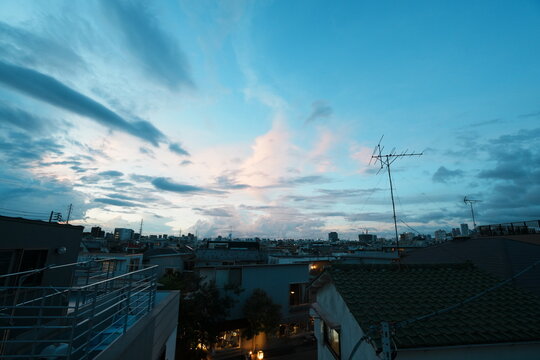 夏の日没後に青みが増した東京の住宅街の空と灯りがともる街並み