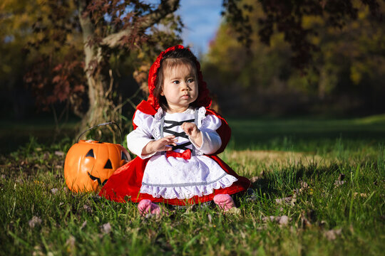 Toddler in Red Hooded Costume Beside Pumpkin Bucket