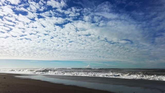 Dramatic mackerel sky with rolling clouds over crashing waves at a Batumi beach shoreline.