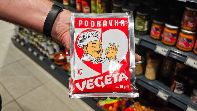 Hand holding vegeta podravka seasoning in supermarket aisle
