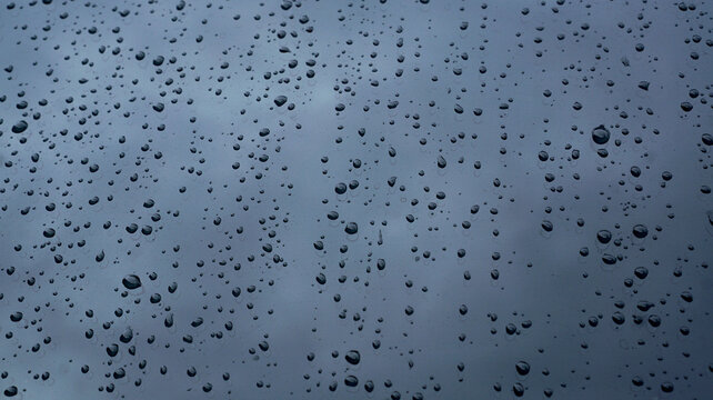 Water droplets on transparent glass. Glistening water drops on the surface of clear, bluish glass.