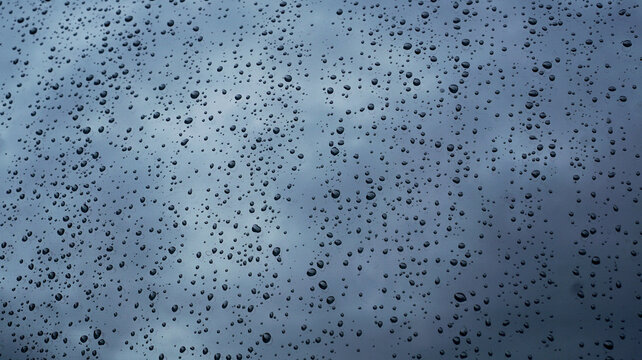 Water droplets on transparent glass. Glistening water drops on the surface of clear, bluish glass.