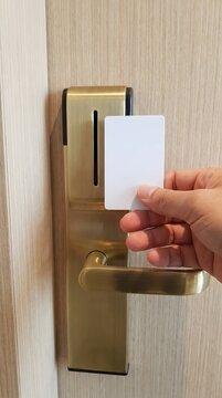 Holding blank white keycard near electronic hotel door lock handle.