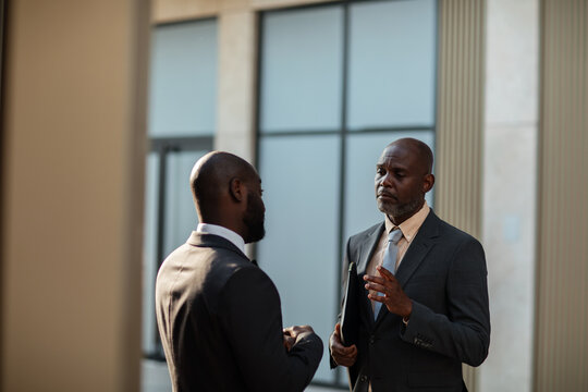 Two business professionals talking in modern office lobby