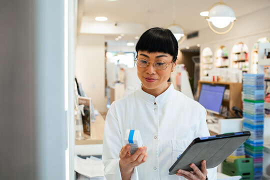 Pharmacist verifying medication with tablet in modern pharmacy
