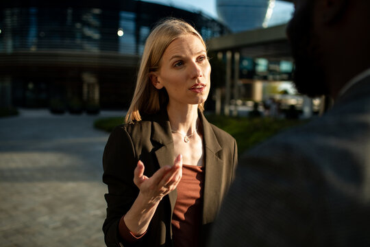 Businesswoman talking with colleague outside modern office